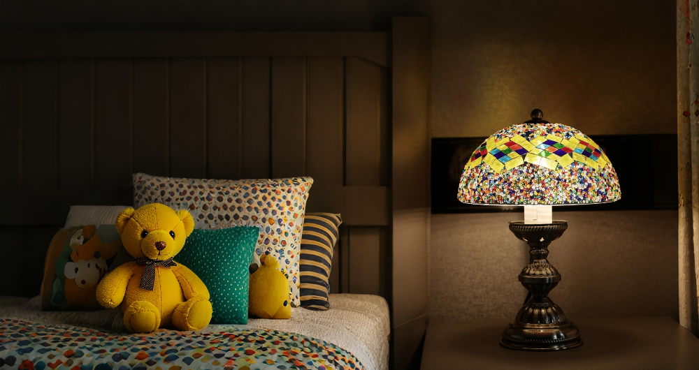 Bedroom scene with teddy bear, pillows, and a mushroom glass shade lamp.