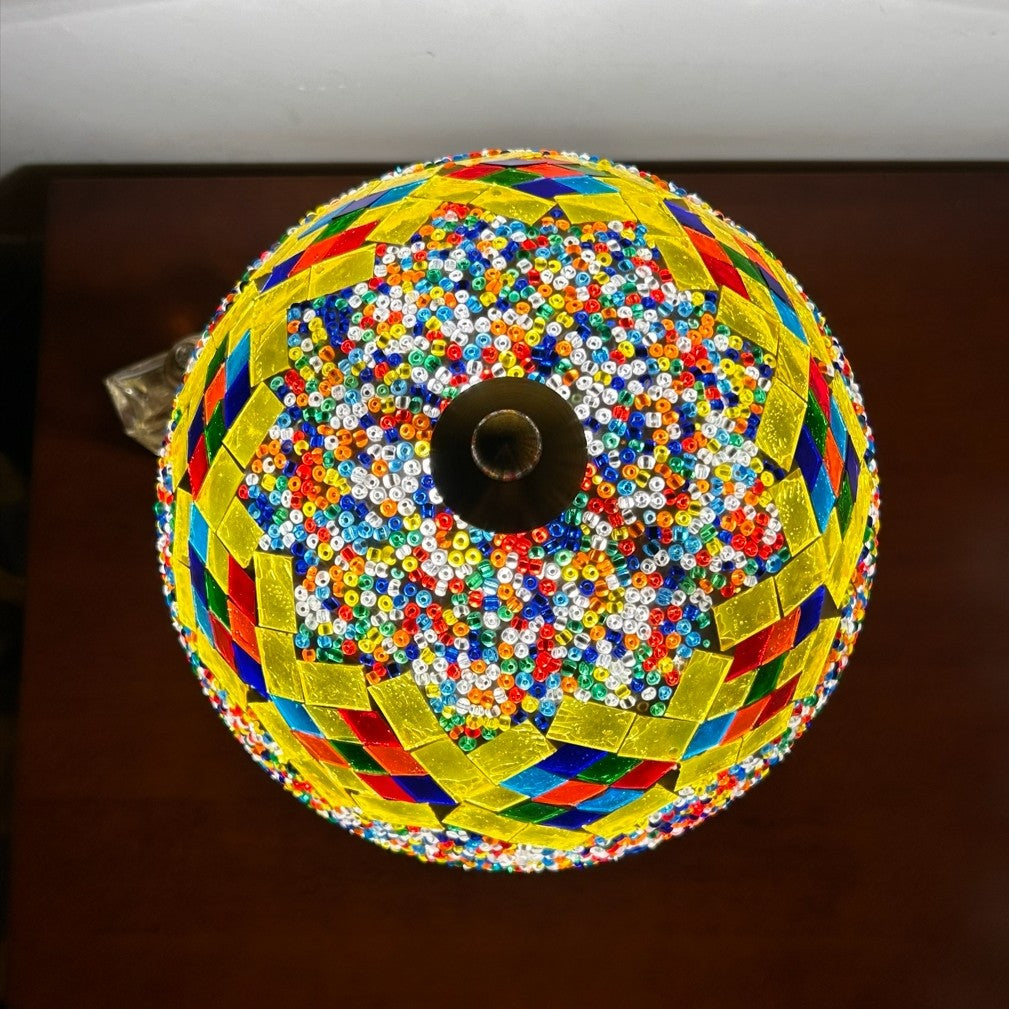 Colorful beaded and woven circular mushroom lamp on a dark surface