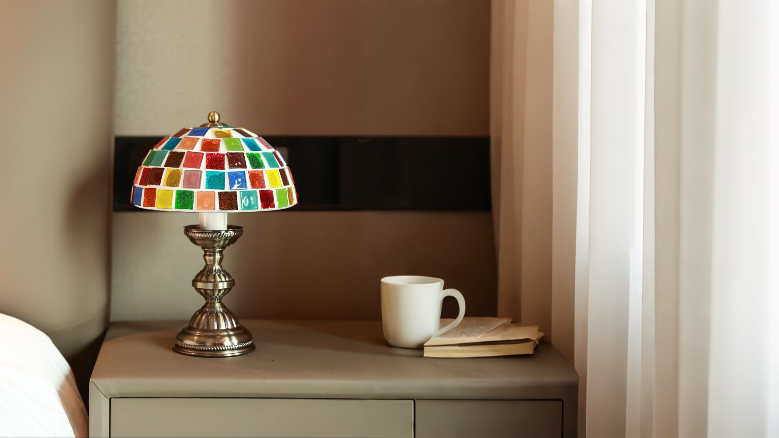 Homira colorful mosaic lamp on a nightstand with a cup and book in a bedroom setting