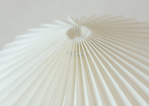 Close-up of a Homira white pleated lampshade against a light background