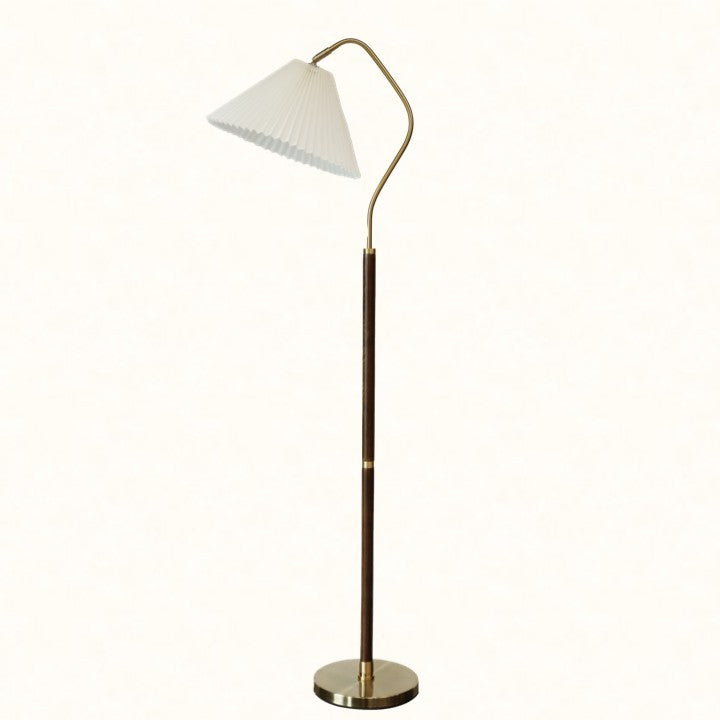 Floor lamp with pleated white shade and curved brass arm on a plain background