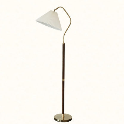 Floor lamp with pleated white shade and curved brass arm on a plain background