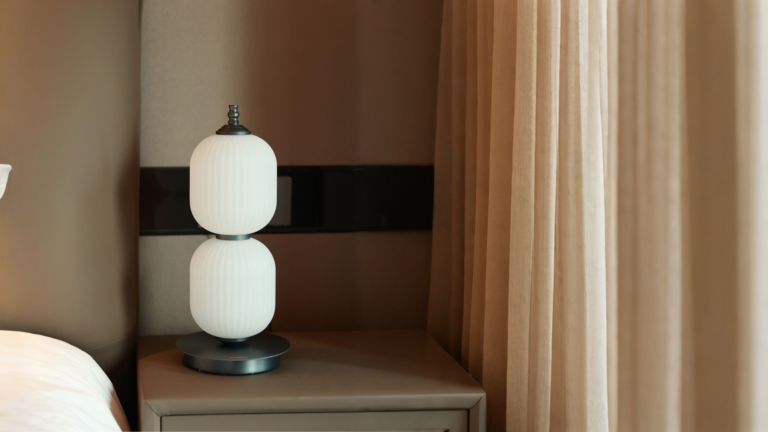 Homira lantern lamp on a nightstand next to a curtain